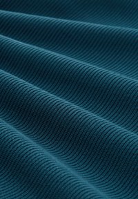 Strukturierter tealfarbener Stoff mit ribbelmuster, sichtbaren Falten und Knitterstellen, die seine gewebte Struktur und Tiefe hervorheben.