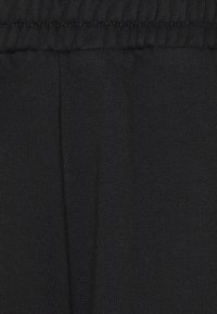 Svart tyg med en jämn textur, med ett midjeband och subtila veck, utformat för komfort och flexibilitet.