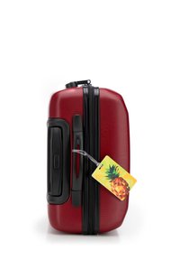 Red hard-shell suitcase with a textured surface, black zipper and handle, featuring a pineapple-shaped luggage tag.