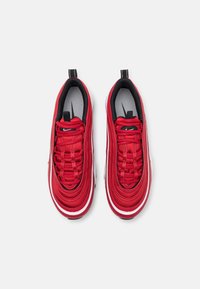 Paire de baskets rouges Nike avec semelles blanches et doublure intérieure noire, vues de dessus sur fond blanc.