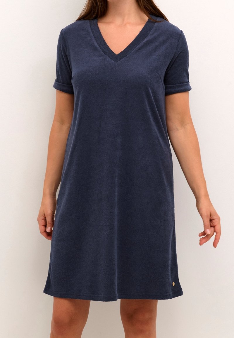 Robe en coton bleu marine avec col en V, manches courtes retroussées et coupe décontractée, ornée d'un petit logo près de l'ourlet.