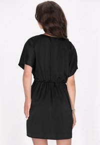 Rochie din satin negru, cu un croi lejer, mâneci scurte și talie elastică. Textură fină și lungime deasupra genunchilor.