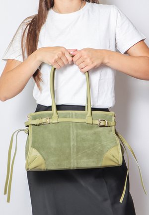 Borsa in suede verde con dettagli in pelle, due manici superiori e una tracolla removibile. Presenta una forma strutturata e legature decorative sui lati.