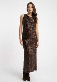 Brązowy, bezrękawnikowy top z cekinami z drapowanym dekoltem, zestawiony z dopasowaną, długą spódnicą z cekinów. Teksturowana tkanina o połyskującej powierzchni.