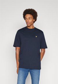Navyblauwe katoenen t-shirt, korte mouwen, ronde hals, met een klein geel logo op de borst, gladde textuur en comfortabele pasvorm.