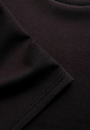 Közelkép egy összegöngyölt fekete szövetről, amelynél látható a szegély varrása, sima textúrával és finom szövés részletekkel.