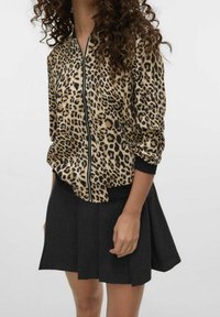 Bomber bunda s leopardím potiskem, černé manžety a zip, spárovaná s skládací černou sukní. Měkká tkanina, ležérní silueta.