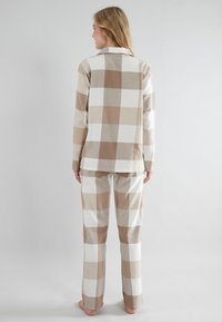 Brown and white plaid pajama set made of soft fabric, featuring a collared top and straight-leg pants, with a relaxed fit and no visible hardware.