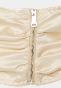 Corset de cetim com detalhes em franzido, na cor bege neutro, com um fecho metálico central com puxador prateado e acabamento em tecido.