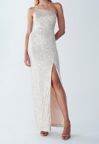 Abito con paillettes in beige chiaro, con una spallina singola, alta apertura laterale e silhouette dritta. Dettagli superficiali testurizzati e scintillanti.