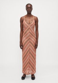 Maxi dress with thin straps, featuring a chevron pattern in warm tones of orange, red, and brown; made from a soft, textured fabric.