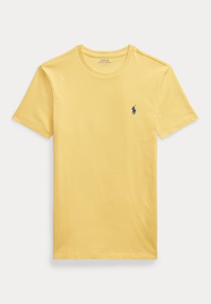 Kollane puuvillane T-särk lühikeste varrukatega, ümar kaelus ja rindkerel väike tumehall tikandiga logo. Sile ja kerge tekstuur.