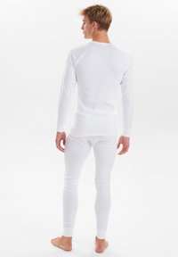 White long-sleeve top and matching leggings made from soft fabric. Long sleeves and fitted design with ribbed cuffs at wrists and ankles.
