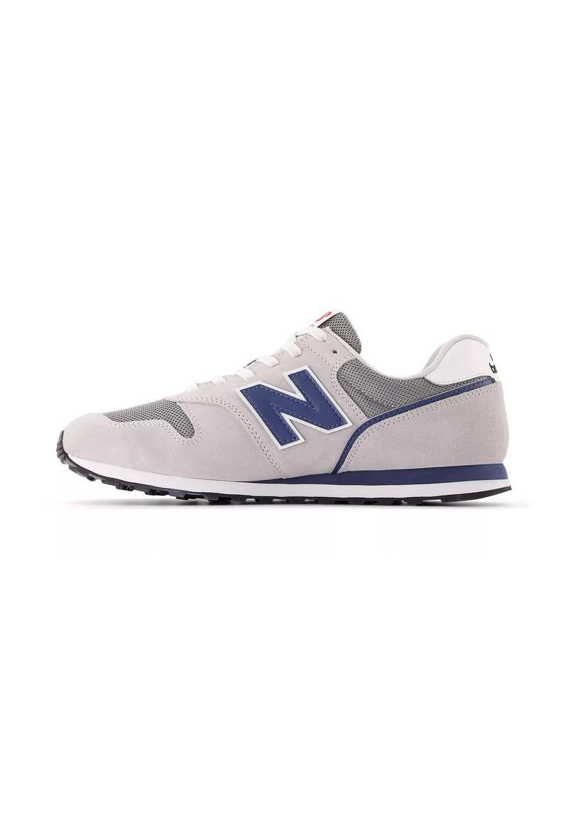 Sneaker grigio chiaro con accenti blu navy, materiali in suede e mesh, design con lacci, suola in gomma e il prominente logo "N" sul lato.