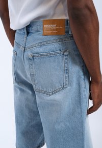 Lichtblauwe denimshorts met een relaxte pasvorm. Heeft twee achterzakken en een bruine leren label op de tailleband met merkinformatie.