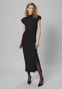 Rochie midi neagră, ajustată, cu mâneci scurte tip cap, fante pe lateral și detaliu pliat la talie, realizată dintr-un material neted și elastic.