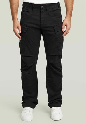 Czarne spodnie cargo o slim fit, z wieloma kieszeniami i lekkim materiałem. Połączone z białymi sneakersami dla kontrastu.