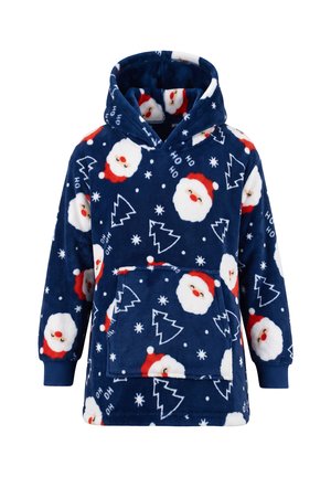 Lächelndes Kind trägt eine übergroße dunkelblaue Kapuzen-Decke mit Weihnachtsmann-Gesichtern, Tannenbäumen und "Ho Ho Ho" Mustern, schwarze Hose und weiße Turnschuhe.