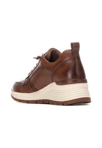Zapatilla de cuero marrón con un acabado texturizado, suela de goma gris-blanca, forma redondeada y cierre con cordones ajustable. La lengüeta trasera presenta un logo.