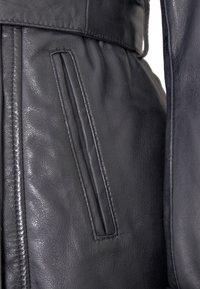 Schwarze Lederjacke mit glatter Textur, schmaler Taille, vertikalen Reißverschlusstaschen und genähten Details entlang der Nähte.