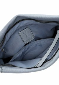 Interno di una borsa a tracolla in pelle grigia, con una tasca con zip, foderatura in tessuto liscio e un'etichetta marchiata con logo in rilievo.
