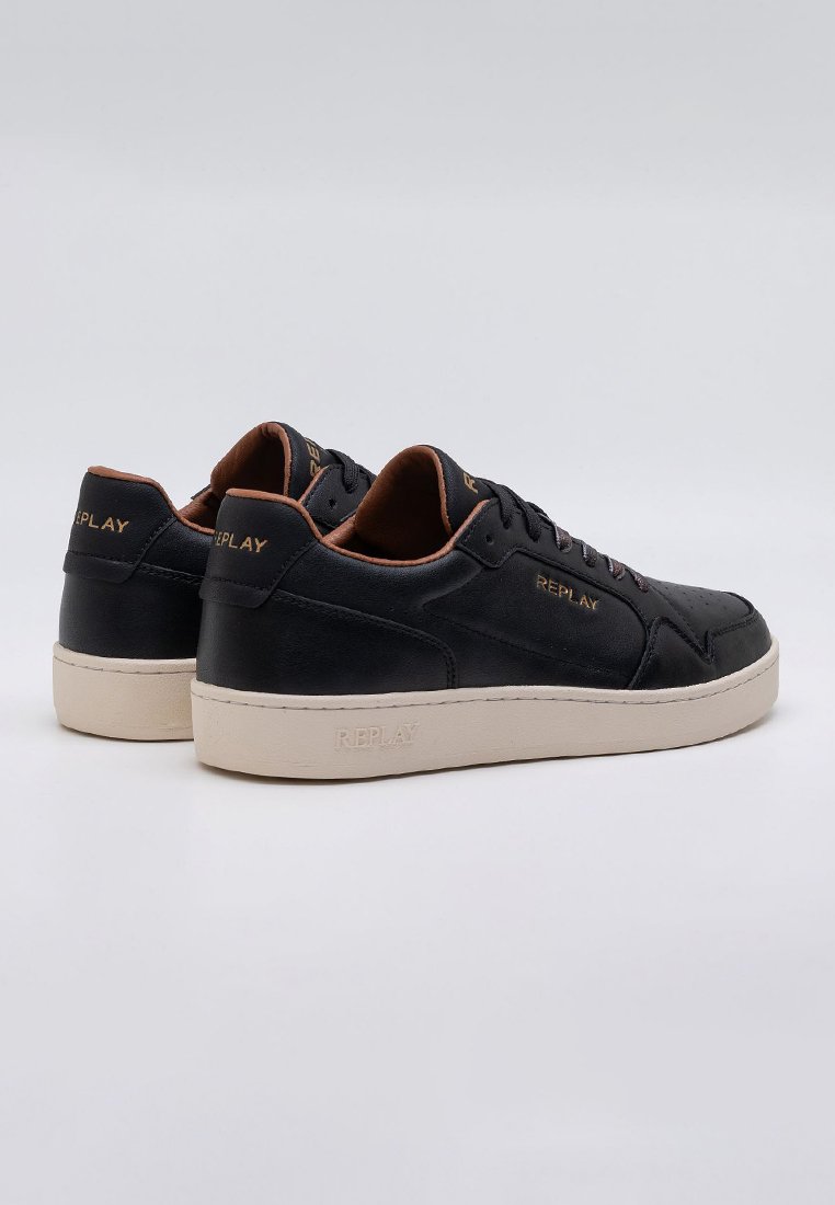 Zwarte leren sneakers met een gladde textuur, beige rubberen zool, gouden logo-accenten en geperforeerde details aan de zijkanten.