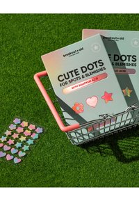 Emballage Cute Dots en vert pastel avec des accents holographiques, contenant des autocollants en forme d'étoile et de fleur, dans un panier métallique avec une poignée rose.