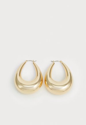 Orecchini a cerchio in tonalità oro con un design curvato e liscio, rifiniti con una superficie lucida. Texture riflettente e chiusura a cerchio sicura.