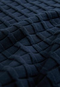 Material textil de culoare bleumarin, cu o textură 3D în formă de rețea, având pătrățele ridicate și o textură moale, țesută, care creează o suprafață tactilă.