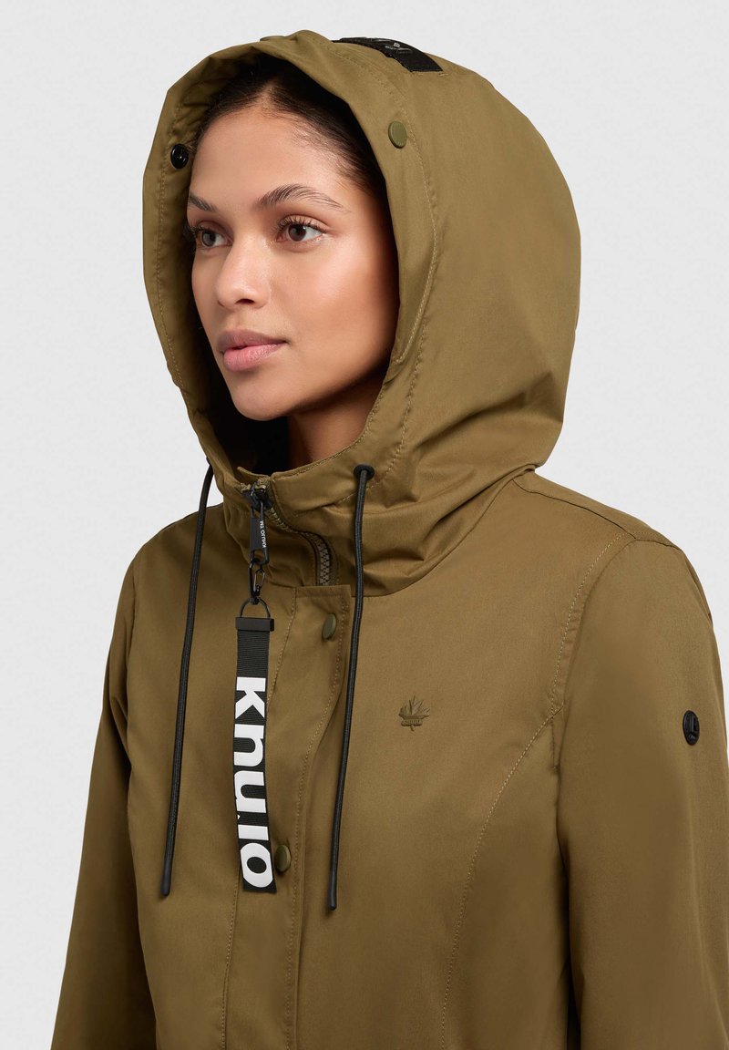Olivgrüne wasserdichte Jacke mit verstellbarem Kapuzenzug, Reißverschluss und Logodetail. Verfügt über Druckknöpfe und eine glatte Textur.