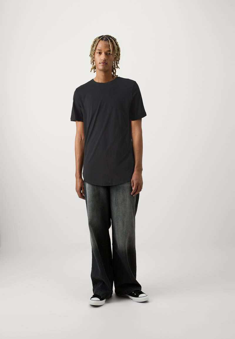Sort kortærmet t-shirt med rund halsudskæring, parret med brede jeans med lys-til-mørk gradient og sorte kanvas sneakers.