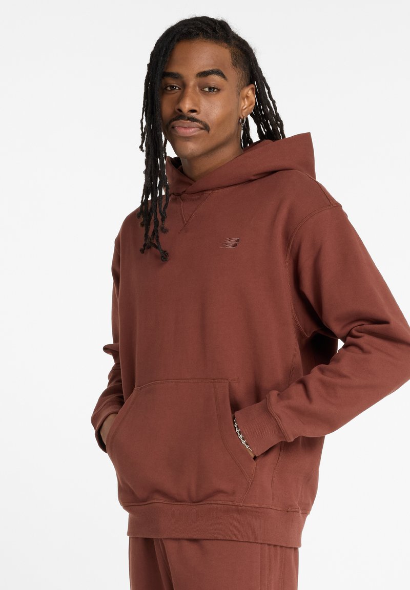 Brown hooded sweatshirt made of cotton blend fabric. Features a front pouch pocket, ribbed cuffs, and a small logo on the chest.