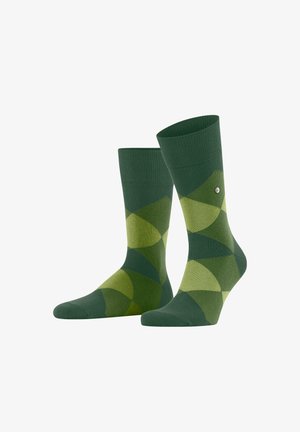 Grüne Socken mit einem geometrischen Muster aus überlappenden Formen in verschiedenen Grüntönen, mit einem kleinen Logo an der Seite.