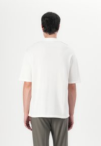 Kortermet, hvit skjorte laget av lett stoff, med rett snitt og minimalistisk design med kontrasterende halsdetaljer.
