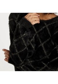 Czarny puszysty sweter z diamentowym wzorem wykończonym metaliczną nitką. Teksturowana powierzchnia z szerokim dekoltem i luźnymi rękawami.