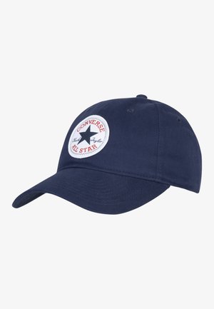 Gorra de béisbol azul marino fabricada en algodón con visera curvada, que presenta un parche redondo blanco con una estrella negra y el texto rojo "Converse All Star."
