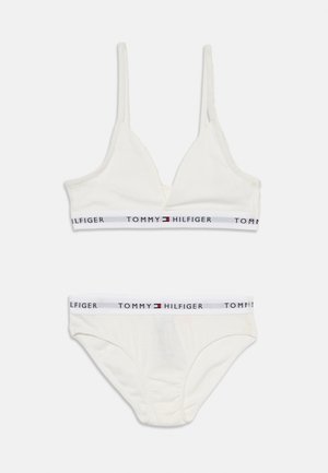 Ensemble en coton blanc composé d'un soutien-gorge et d'un culotte avec des bretelles ajustables. Il présente une taille élastique de marque en bleu marine et rouge, avec un design minimaliste.