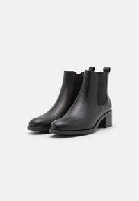 Bottines en cuir noir avec un bout arrondi, des panneaux latéraux élastiques et un talon carré. Texture lisse avec des détails de couture minimaux.