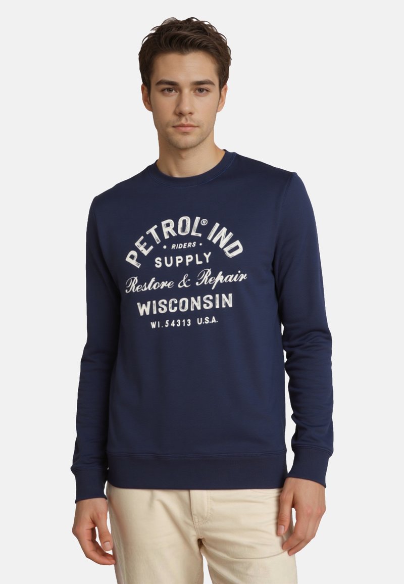 Námornícka modrá mikina s dlhými rukávmi, okrúhlym výstrihom a bielym potlačou s nápismi "PETROL IND SUPPLY" a "WISCONSIN" na hrudi.