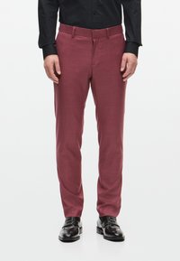 Burgundi színű nadrág texturált anyagból, slim fit szabású, övcsatolókkal és oldalsó zsebekkel, fekete fényes loaferekkel és fekete inggel párosítva.