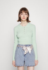 Top de manga longa canelado verde menta com colarinho polo, cinco botões, combinado com calções de ganga de cintura alta com um cinto de tecido estampado.