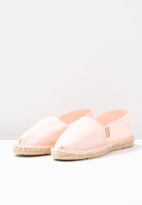 Pink canvas espadrilles with an open toe design and a woven jute sole. Features stitching along the edges and a small brand tag on the side.