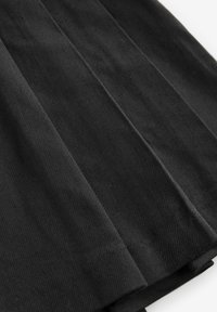 Tissu plissé noir mettant en valeur une surface texturée avec des crêtes distinctes et une finition lisse. Les accents sont minimalistes sans qu'aucune quincaillerie visible.
