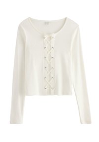 Hvid, ribbet, cropped langærmet top med snøredetalje foran med sølvfarvede øjer og rund halsudskæring. Blød tekstur, tætsiddende design.