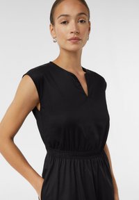 Czarna sukienka bez rękawów z dekoltem w serek i elastyczną talią. Gładki materiał o luźnym kroju, z bocznymi kieszonkami.