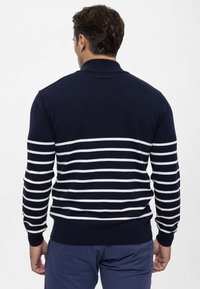 Marineblauwe gebreide trui met horizontale witte strepen, geribbelde boorden en zoom, ontworpen voor een aansluitende pasvorm, met een klassieke kraag.