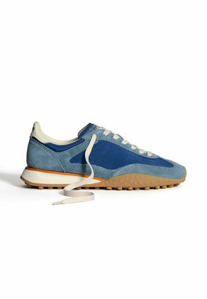 Zapatillas de ante azul con una parte superior en azul claro y navy, cordones crema y una suela beige texturizada. Presenta un diseño deportivo y acentos contrastantes.