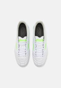 Scarpe atletiche bianche con accenti verdi, dotate di un upper in sintetico testurizzato, design con lacci e colletto imbottito.