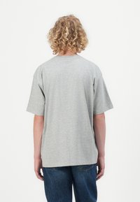 Graues Baumwoll-T-Shirt mit kurzen Ärmeln, lockerer Passform und Rundhalsausschnitt, von hinten betrachtet. Sanfte Textur ohne sichtbare Muster.