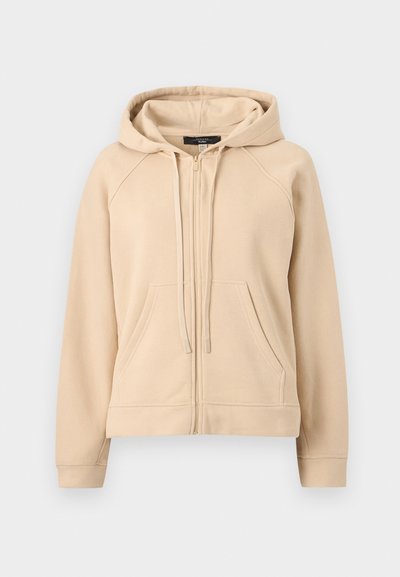 Μπεζ φούτερ με φερμουάρ, κουκούλα με κορδόνι και μπροστινές τσέπες τύπου καγκουρό, απεικονίζεται σε απλό ανοιχτό γκρι φόντο.